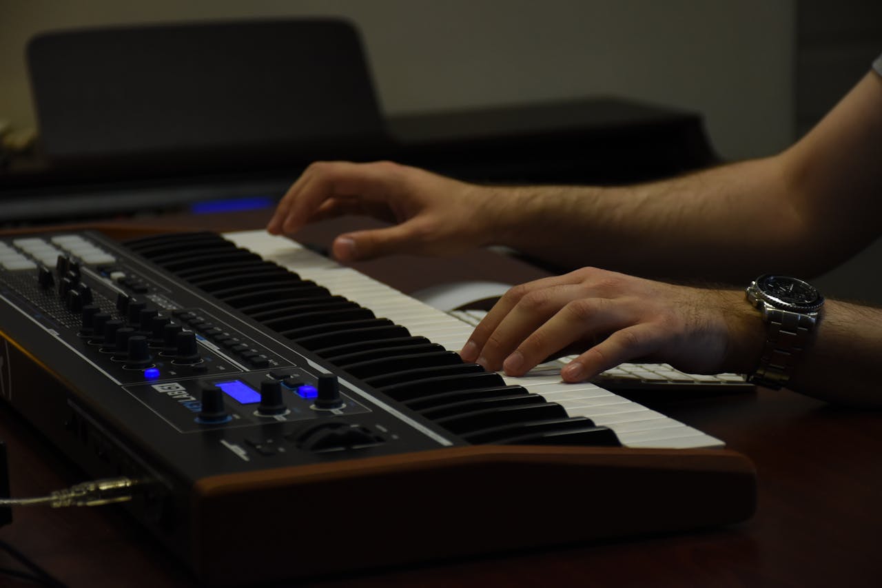 Close-up of hands playing a MIDI keyboard in a music studio. Creative atmosphere.